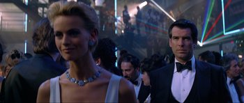 Movie still from “Tomorrow Never Dies” (1997), directed by Roger Spottiswoode – A group of people standing in a room at a party; Medium shot, Over the shoulder angle