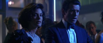 Movie still from “Tomorrow Never Dies” (1997), directed by Roger Spottiswoode – A man and a woman in a suit and tie in a room; Close Up shot, Low angle