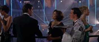 Movie still from “Tomorrow Never Dies” (1997), directed by Roger Spottiswoode – A man and a woman holding a tray in front of two other people; Medium shot, Over the shoulder angle