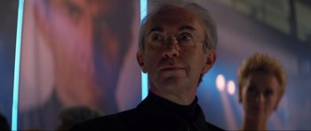 Movie still from “Tomorrow Never Dies” (1997), directed by Roger Spottiswoode – An older man wearing glasses looking to his left; Close Up shot, Low angle