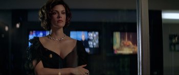 Movie still from “Tomorrow Never Dies” (1997), directed by Roger Spottiswoode – A woman in a black dress standing in front of a television; Close Up shot, Low angle