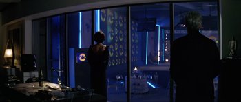 Movie still from “Tomorrow Never Dies” (1997), directed by Roger Spottiswoode – A woman standing in front of a window in a dark room; Wide shot, Over the shoulder angle