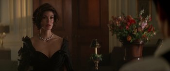Movie still from “Tomorrow Never Dies” (1997), directed by Roger Spottiswoode – A woman in a black dress standing next to a table; Medium shot, Over the shoulder angle