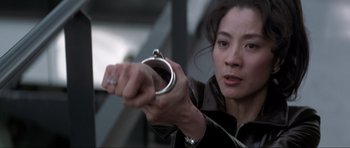 Movie still from “Tomorrow Never Dies” (1997), directed by Roger Spottiswoode – A woman holding a gun in her hand; Close Up shot, Low angle
