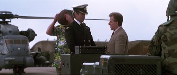 A man in a suit talking to a man in a military uniform