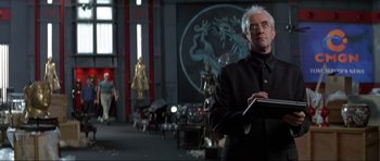 Movie still from “Tomorrow Never Dies” (1997), directed by Roger Spottiswoode – An older man holding a tablet in front of a wall; Medium shot, Low angle