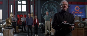 Movie still from “Tomorrow Never Dies” (1997), directed by Roger Spottiswoode – A group of people standing in front of a man; Medium shot, Over the shoulder angle
