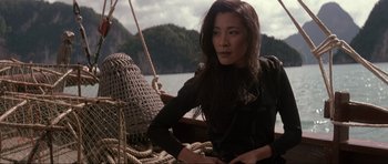 Movie still from “Tomorrow Never Dies” (1997), directed by Roger Spottiswoode – A woman sitting on top of a boat in the water; Medium shot, Low angle