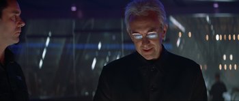 Movie still from “Tomorrow Never Dies” (1997), directed by Roger Spottiswoode – A man in a black jacket and glasses; Close Up shot, Low angle