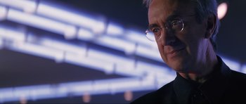 Movie still from “Tomorrow Never Dies” (1997), directed by Roger Spottiswoode – A person wearing glasses and a suit; Close Up shot, Over the shoulder angle