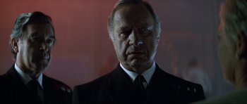 Movie still from “Tomorrow Never Dies” (1997), directed by Roger Spottiswoode – An older man wearing a suit and tie; Close Up shot, Low angle