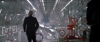 Movie still from “Tomorrow Never Dies” (1997), directed by Roger Spottiswoode – A man standing in front of an industrial building; Wide shot, Low angle