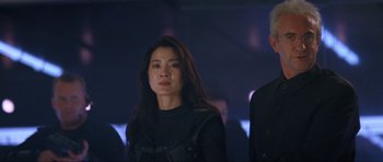 Movie still from “Tomorrow Never Dies” (1997), directed by Roger Spottiswoode – A woman standing next to a man in a dark room; Close Up shot, Low angle