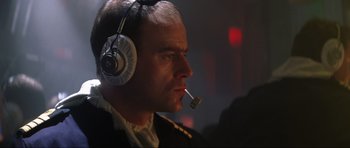 Movie still from “Tomorrow Never Dies” (1997), directed by Roger Spottiswoode – A person wearing headphones and smoking a cigarette; Close Up shot, Low angle