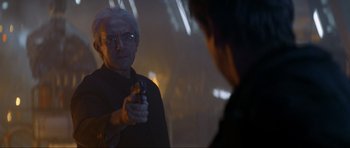 Movie still from “Tomorrow Never Dies” (1997), directed by Roger Spottiswoode – An older man holding a gun in front of a mirror; Close Up shot, Over the shoulder angle