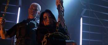 Movie still from “Tomorrow Never Dies” (1997), directed by Roger Spottiswoode – A man and a woman chained to each other in a dark room; Medium shot, Low angle