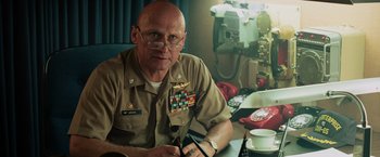 Movie still from “Top Gun” (1986), directed by Tony Scott – A man in uniform sitting in front of a table; Medium shot, Low angle