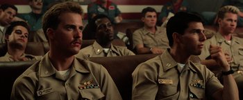 Movie still from “Top Gun” (1986), directed by Tony Scott – A group of men sitting in a room watching a movie; Medium shot, Low angle