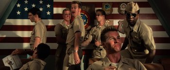 Movie still from “Top Gun” (1986), directed by Tony Scott – A group of young men standing next to each other in front of an american flag; Medium shot, Low angle