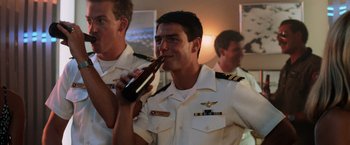 Movie still from “Top Gun” (1986), directed by Tony Scott – A man in a uniform drinking a bottle of beer; Medium shot, Low angle