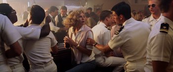 Movie still from “Top Gun” (1986), directed by Tony Scott – A group of people are gathered around a bar; Medium shot, Over the shoulder angle