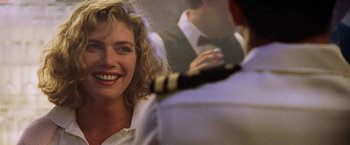 Movie still from “Top Gun” (1986), directed by Tony Scott – A woman smiles in front of a mirror while holding a tie; Close Up shot, Over the shoulder angle