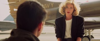Movie still from “Top Gun” (1986), directed by Tony Scott – A man and a woman sitting in front of an airplane; Medium shot, Over the shoulder angle