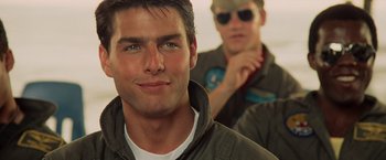 Movie still from “Top Gun” (1986), directed by Tony Scott – A man in a green jacket is looking at the camera; Close Up shot, Low angle