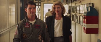 Movie still from “Top Gun” (1986), directed by Tony Scott – A man and a woman are walking in a hallway; Medium shot, Low angle