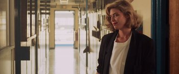Movie still from “Top Gun” (1986), directed by Tony Scott – A woman standing in the hallway of a building; Medium shot, Over the shoulder angle