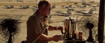 Movie still from “Top Gun” (1986), directed by Tony Scott – An older man in a military uniform pouring a beverage from a coffee pot; Medium shot, High angle
