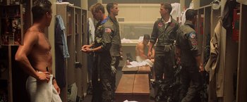 Movie still from “Top Gun” (1986), directed by Tony Scott – A group of men standing next to each other in a room; Wide shot, Low angle