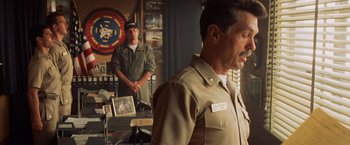 Movie still from “Top Gun” (1986), directed by Tony Scott – A man in a uniform standing in front of another man in a uniform; Medium shot, Over the shoulder angle