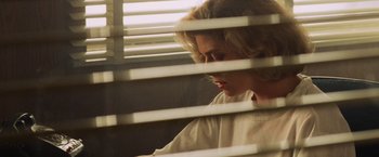 Movie still from “Top Gun” (1986), directed by Tony Scott – A woman sitting in front of a window with blinds; Close Up shot, Low angle