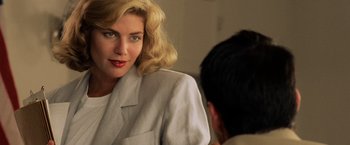 Movie still from “Top Gun” (1986), directed by Tony Scott – A woman in a white jacket is talking to a man in a black suit; Close Up shot, Over the shoulder angle