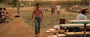 Movie still from “Top Gun” (1986), directed by Tony Scott – A group of people standing on top of a sandy beach; Wide shot, Low angle