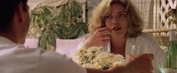 Movie still from “Top Gun” (1986), directed by Tony Scott – A woman sitting in front of a bouquet of flowers; Close Up shot, Over the shoulder angle