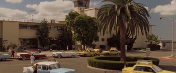 Movie still from “Top Gun” (1986), directed by Tony Scott – A bunch of cars are parked in a parking lot; Extreme Wide shot, High angle