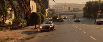 Movie still from “Top Gun” (1986), directed by Tony Scott – A car driving down a street next to a street light; Extreme Wide shot, High angle