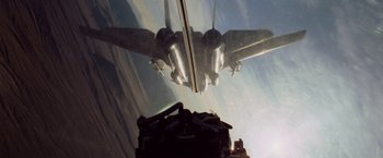Movie still from “Top Gun” (1986), directed by Tony Scott – An image of an airplane flying through the sky; Wide shot, Overhead angle
