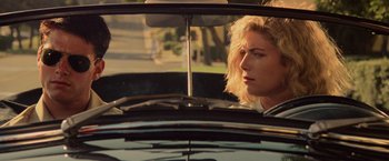 Movie still from “Top Gun” (1986), directed by Tony Scott – A woman sitting in the back seat of a car looking out the window; Close Up shot, Over the shoulder angle