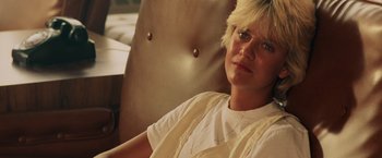 Movie still from “Top Gun” (1986), directed by Tony Scott – A woman sitting in a chair looking into the distance; Close Up shot, Low angle