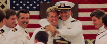 Movie still from “Top Gun” (1986), directed by Tony Scott – A couple of men in uniform hugging each other; Medium shot, Low angle