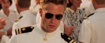 Movie still from “Top Gun” (1986), directed by Tony Scott – A person wearing a uniform and sunglasses; Close Up shot, Low angle