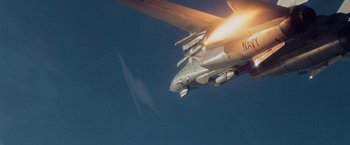 Movie still from “Top Gun” (1986), directed by Tony Scott – An airplane is flying through the air with its landing gear down; Wide shot, Low angle