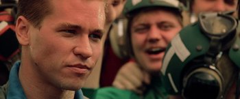 Movie still from “Top Gun” (1986), directed by Tony Scott – Two young men are listening to music while one of them is wearing headphones; Close Up shot, Over the shoulder angle