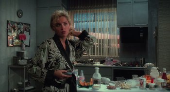 Movie still from “Total Recall” (1990), directed by Paul Verhoeven – A woman holding a cell phone while standing in a kitchen; Medium shot, Over the shoulder angle