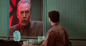 Movie still from “Total Recall” (1990), directed by Paul Verhoeven – A man sitting in front of a mirror and looking at himself in the mirror; Medium shot, Over the shoulder angle
