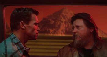 Movie still from “Total Recall” (1990), directed by Paul Verhoeven – Two men standing next to each other in front of a painting; Close Up shot, Over the shoulder angle