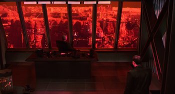 Movie still from “Total Recall” (1990), directed by Paul Verhoeven – A man sitting in front of a large window with a view of a city; Wide shot, High angle